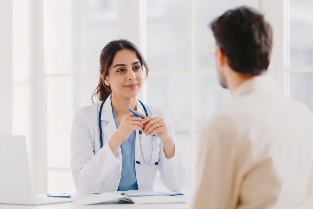 Female doctor sitting at her desk and listening to a patient at a no insurance medical clinic.