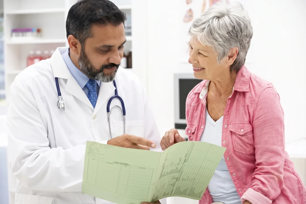 Male doctor reviewing a medical chart with a smiling senior woman at a no insurance medical clinic.