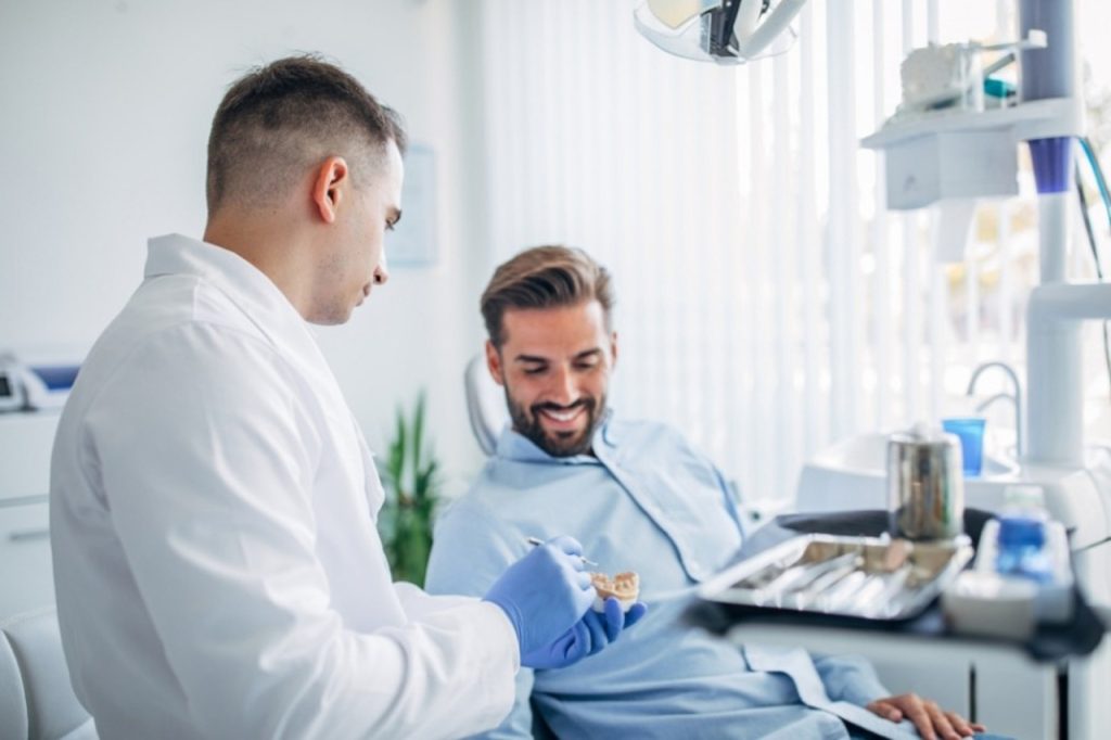 Professional dentist showing a tooth model to a patient during a preventive & wellness care visit in Houston TX.