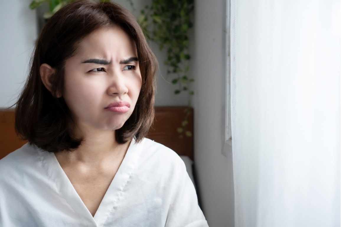 Pensive woman looking out window, searching for psychiatry consultations care in Houston, TX to manage her symptoms.