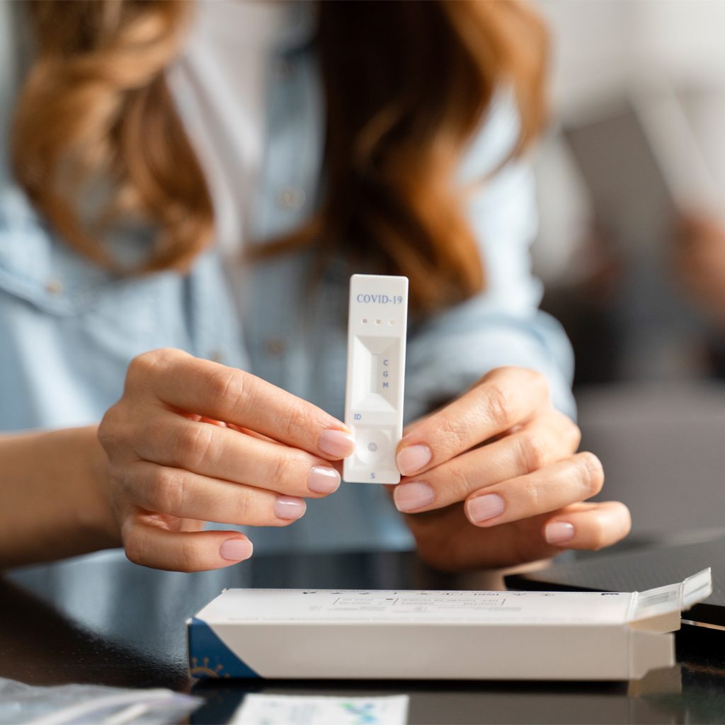 A woman holding a diagnostic testing cassette to check results after completing affordable rapid tests in Houston.