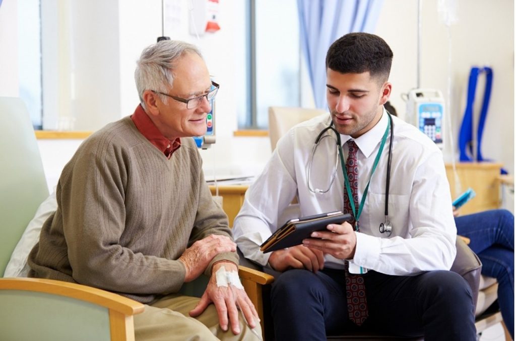 Male physician using a tablet to explain results for preventive & wellness care in Houston to an older patient