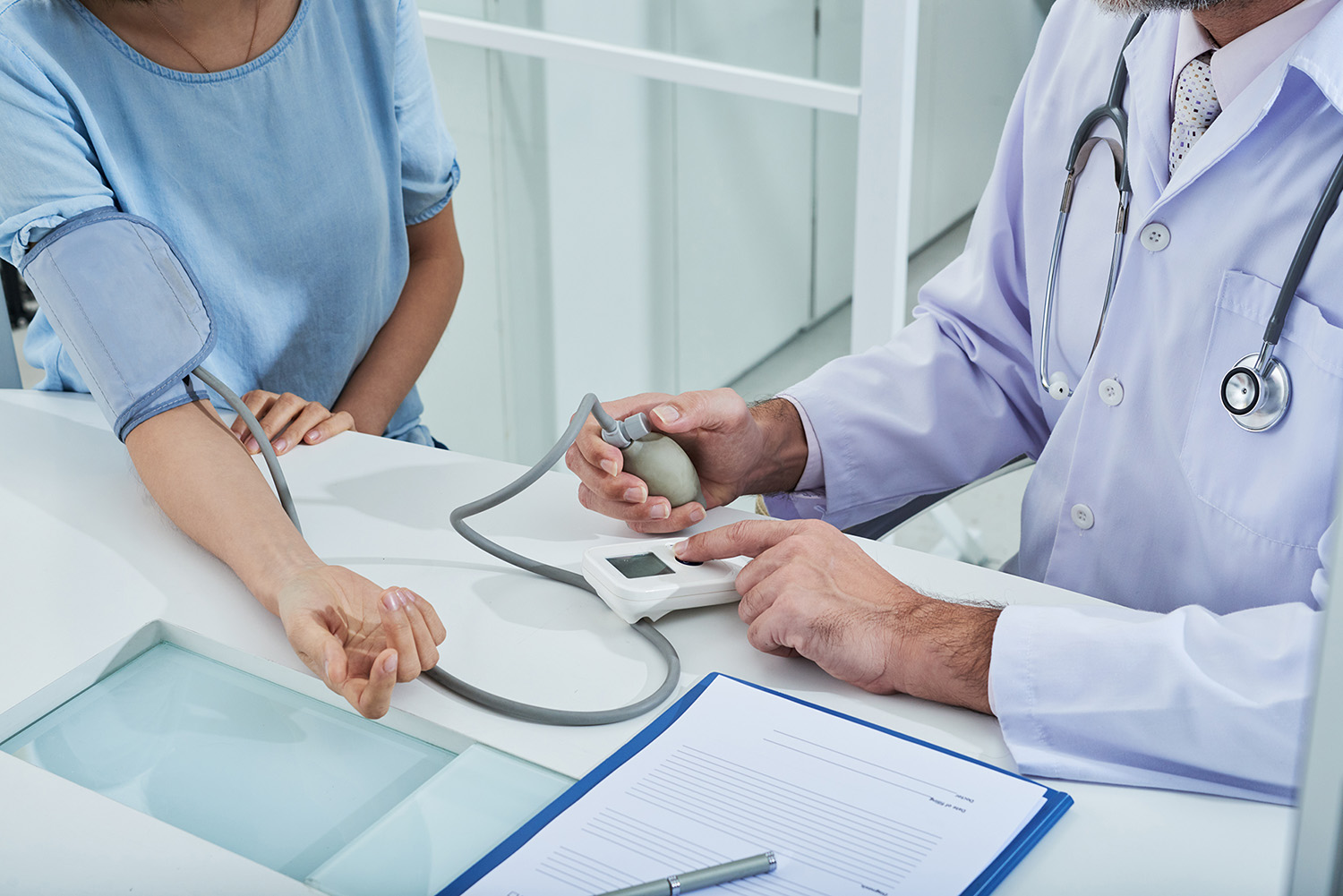 A doctor uses a tonometer for on-site testing and procedures to measure a patient's blood pressure during an exam.