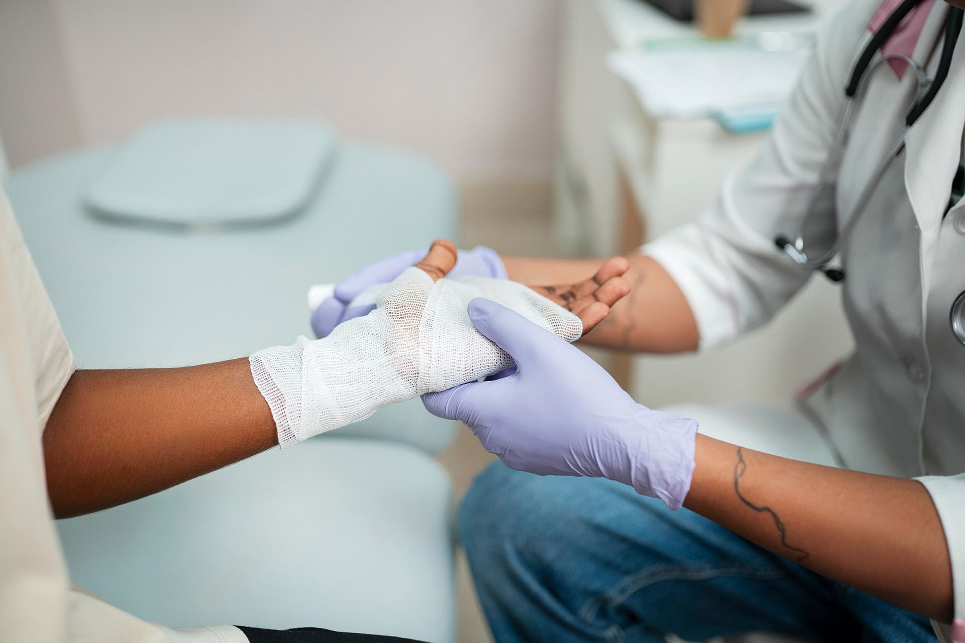 Healthcare professional bandages a patient's hand during routine on-site testing and procedures at a local clinic.